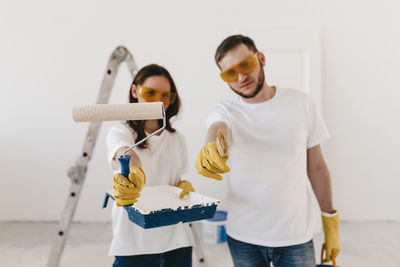 Happy smiling married couple engaged in renovation repair in the room of the house preparing to move