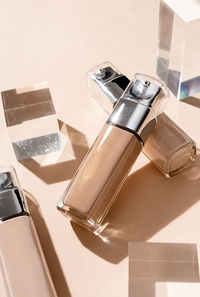 Foundation beauty product is glass bottle with glass cubes and prisms, hard shadows
