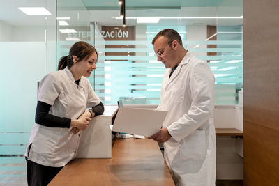 Doctor and nurse discussing on medical record at reception desk in hospital