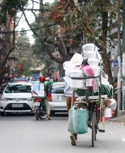 Vendor with kitchen utensils over bicycle on road