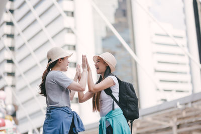 Tourists doing high five while standing in city
