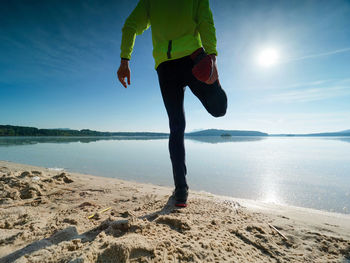 Tall slim man doing stretching on the beach on a sunny morning. body stretching before doing sports.