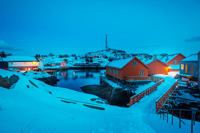 Snow covered houses roof against clear blue sky during dusk