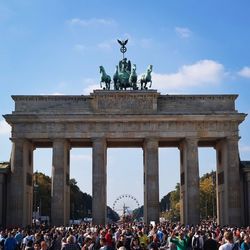 Tourists at brandenburg gate against sky