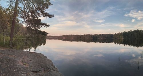 Scenic view of lake by trees against sunset sky