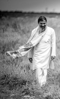 Senior man walking on grass field against sky