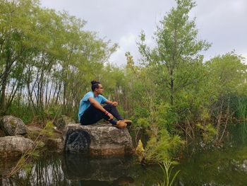 Man sitting on rock against trees