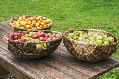 Wicker baskets with apples on old wooden table in the garden