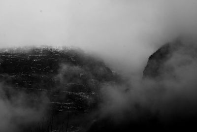 Scenic view of mountains in foggy weather against sky