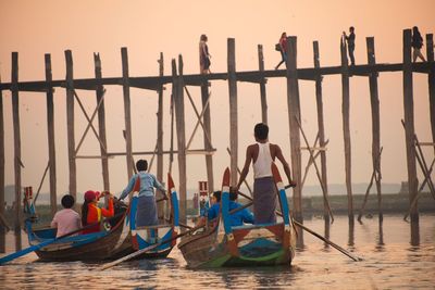 Men standing on boat moored in sea against clear sky