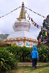 Full length rear view of little boy walking toward a stupa