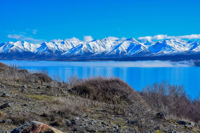 Scenic view of snowcapped mountains and lake against blue sky