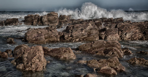 Scenic view of rocks in sea against sky