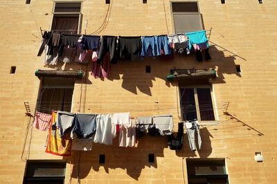 Low angle view of clothes drying against building between windows