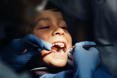 Dentist operating cheerful boy in medical clinic