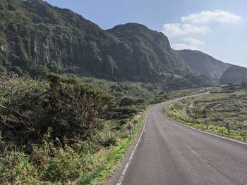 Road leading towards mountains against sky