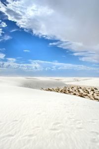 Scenic view of sand dune against cloudy sky