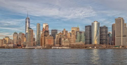 Sea by modern buildings against sky in city