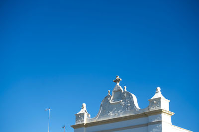 Low angle view of cross on white church against clear blue sky