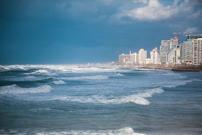 Sea and buildings in city against sky