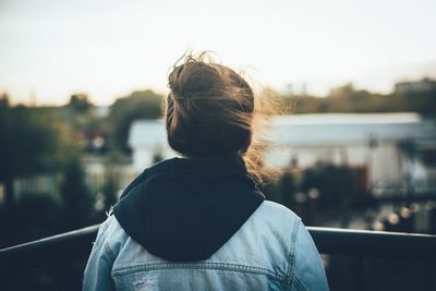 Rear view of woman standing against sky during sunset