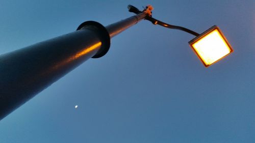 Low angle view of illuminated street light against blue sky