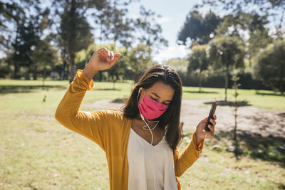 Young woman using smart phone while standing on field