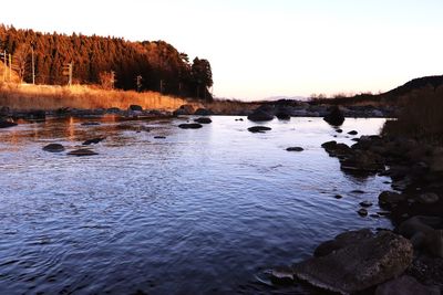 Scenic view of river against sky at sunset