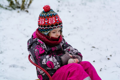 Pensive child sitting on sledging, winter activities for children