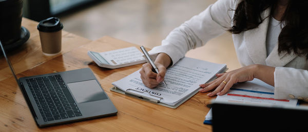 Midsection of woman businesswoman signing document