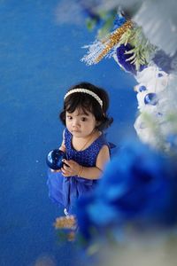 High angle view of cute baby girl holding decoration standing outdoors