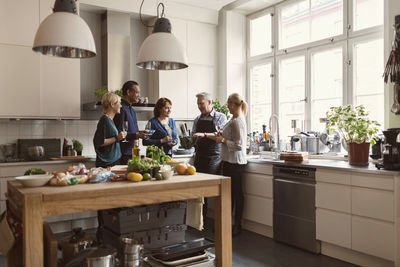 Chef showing savoy cabbage to students while standing in kitchen