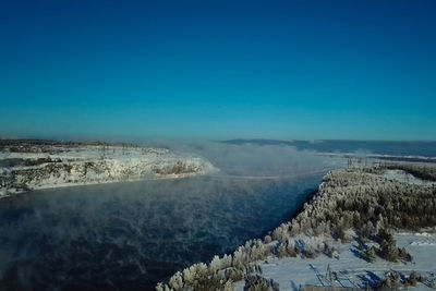 Aerial view of snowcapped mountains against clear blue sky