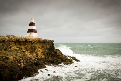 Lighthouse by sea against sky