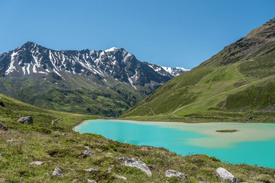 Scenic view of lake and mountains against clear blue sky