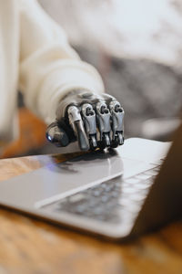 Cropped hand of man using laptop on table