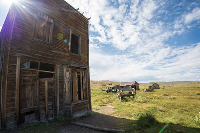 Abandoned wagon near old west wooden building in ghost town on land against sky