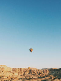 Hot air balloons flying over land against clear blue sky