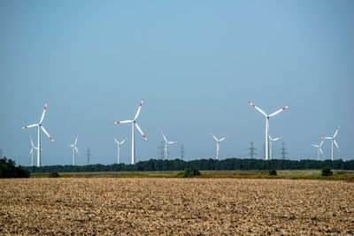 Wind turbines on field against clear sky