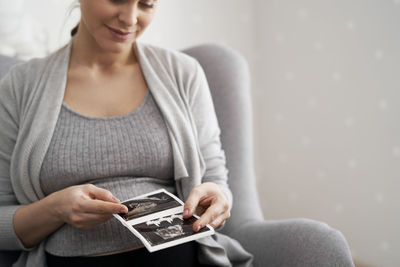 Pregnant woman holding ultrasound photograph