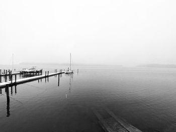 Wooden posts in sea against sky