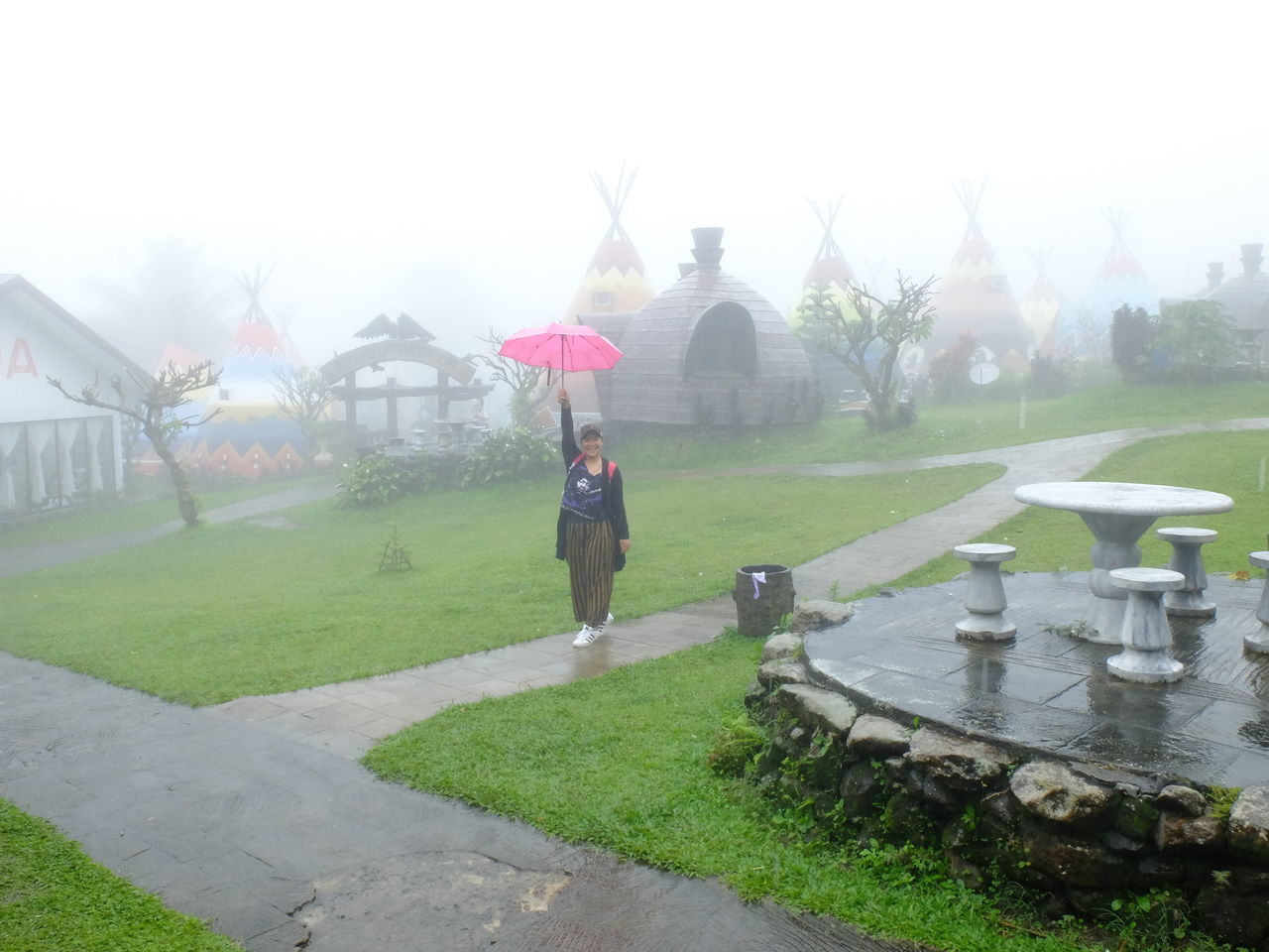 WOMAN STANDING ON FIELD BY BUILT STRUCTURE AGAINST SKY