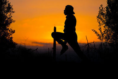 Side view of silhouette man against orange sky