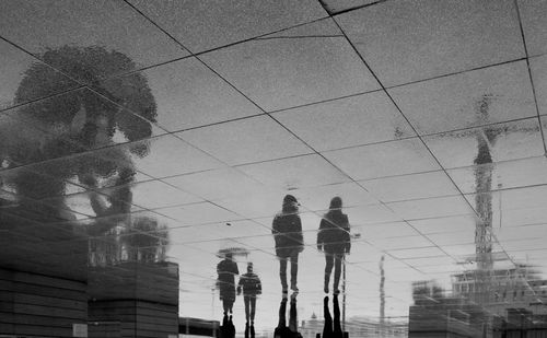 Low angle view of people walking against sky in city