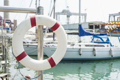 Close-up of life belt hanging on railing at harbor