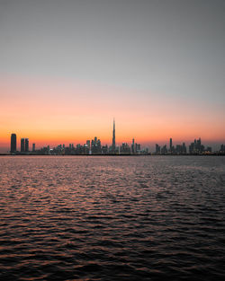 Scenic view of river by buildings against sky during sunset