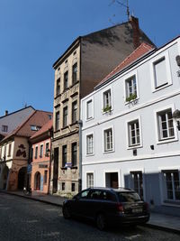 Cars on street by buildings against sky