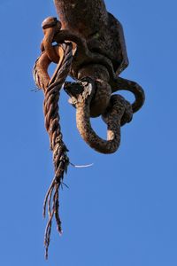 Low angle view of chain tied up against blue sky