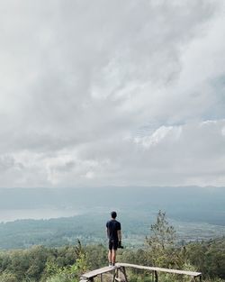 Rear view of man looking at mountain against sky