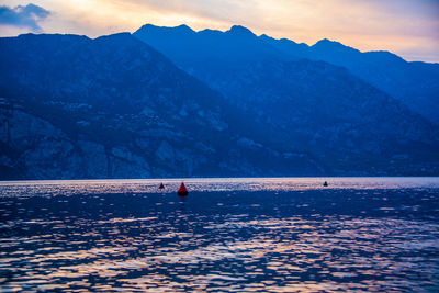 People on mountain by lake against sky